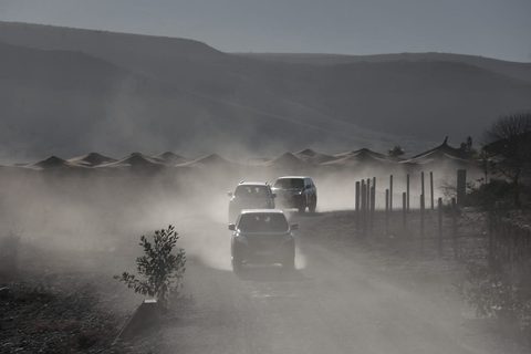 Drei Geländewagen auf einer staubigen Piste nahe einem Wüstencamp