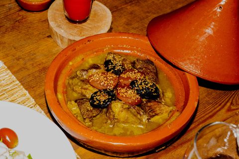 Tajine mit Fleisch, Backpflaumen und Aprikosen, mit Sesam bestreut, in einer Terrakottaschale