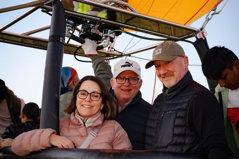 Smiling passengers in the basket, burner lit in the early morning