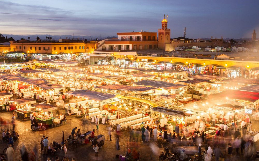 Beleuchtete Essensstände auf dem Platz Jemaa el-Fna in Marrakesch in der Dämmerung