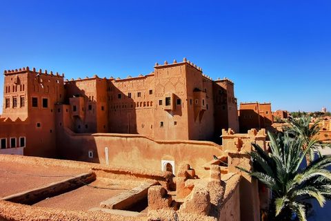 Ockerrote Kasbah mit Zinnentürmen und Palmen im Süden Marokkos